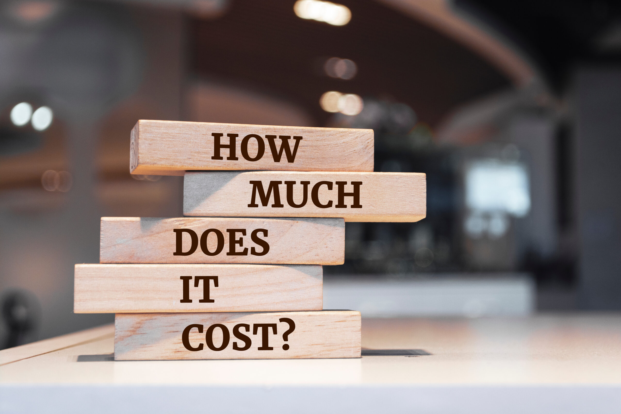 Wooden blocks stacked on a desk that read How Much Does It Cost, the question behind how much does a bookkeeper cost.
